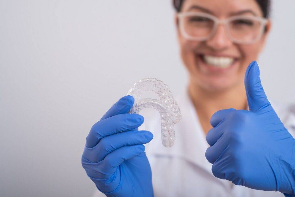 The orthodontist holds the removable transparent retainers